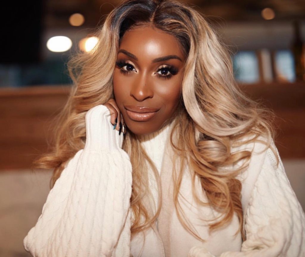 Jackie Aina staring in a white sweater.